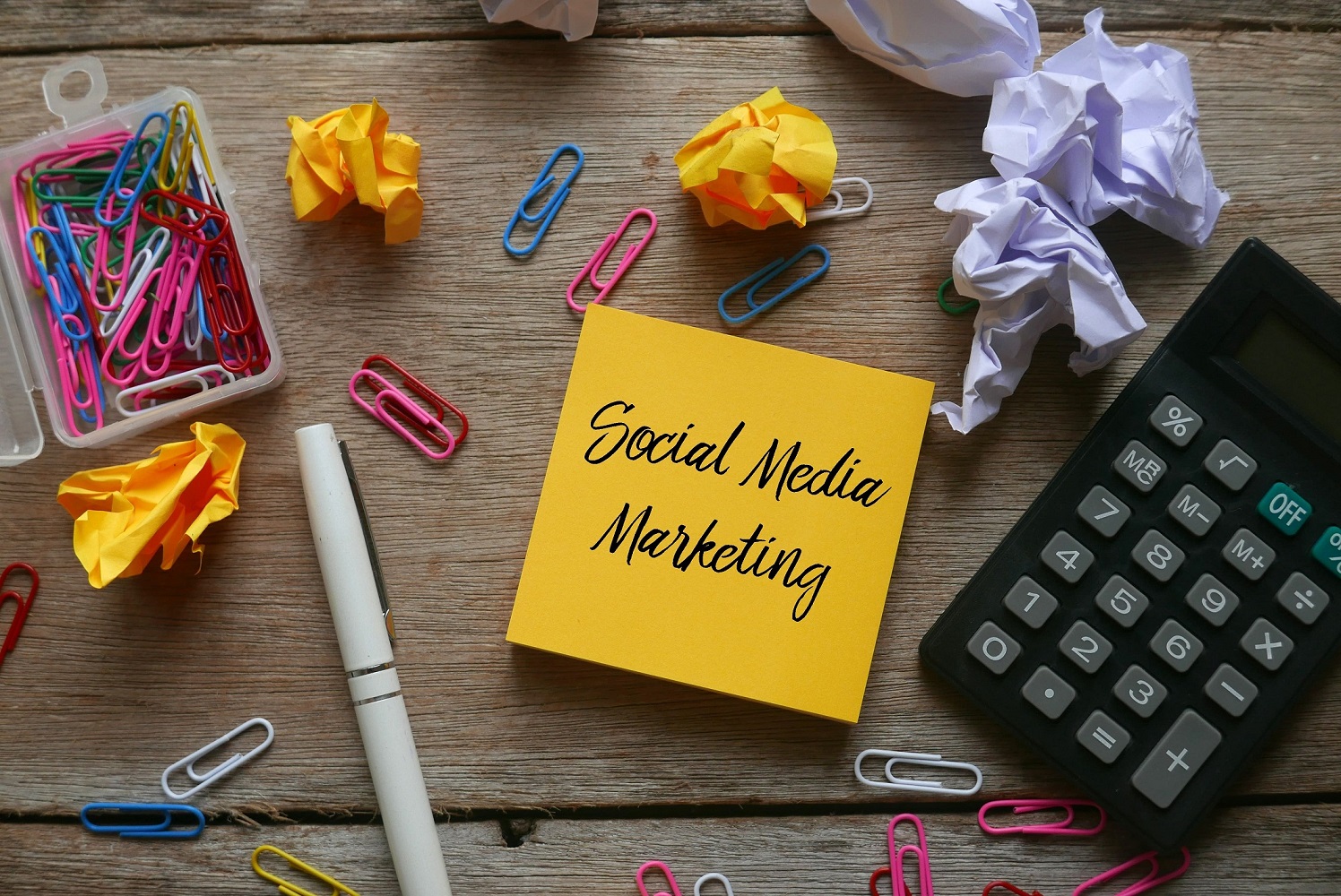 A note with the words social media marketing surrounded by office supplies.